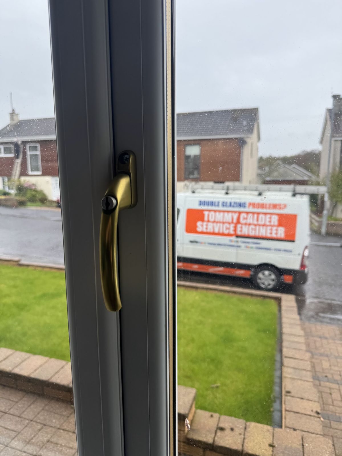 A window handle in the foreground and the Tommy Calder Service Engineer van parked outside
