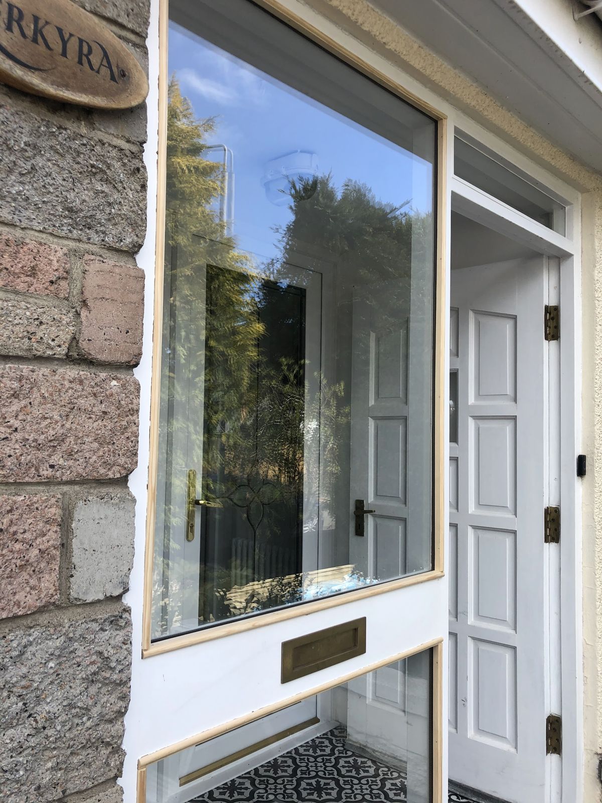 A front door and tall glazed side panel set in a stone porch
